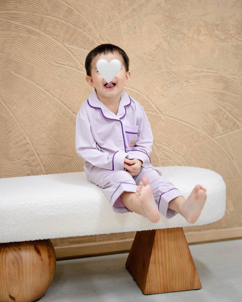 Child wearing LeBear × Em Obsessed OEKO-TEX® bamboo lavender kids pyjamas sitting on a sofa