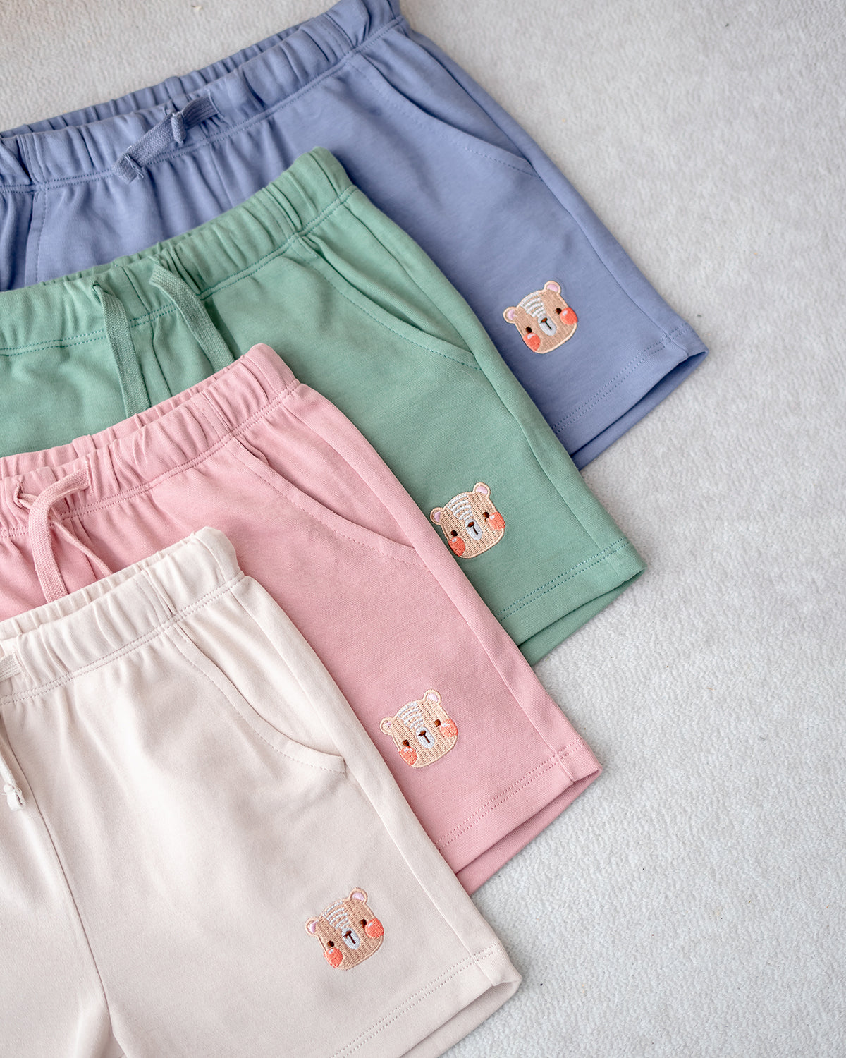 LeBear kids jogger shorts bundle in pastel blue, green, pink, and cream with embroidered bear logo, made from premium cotton