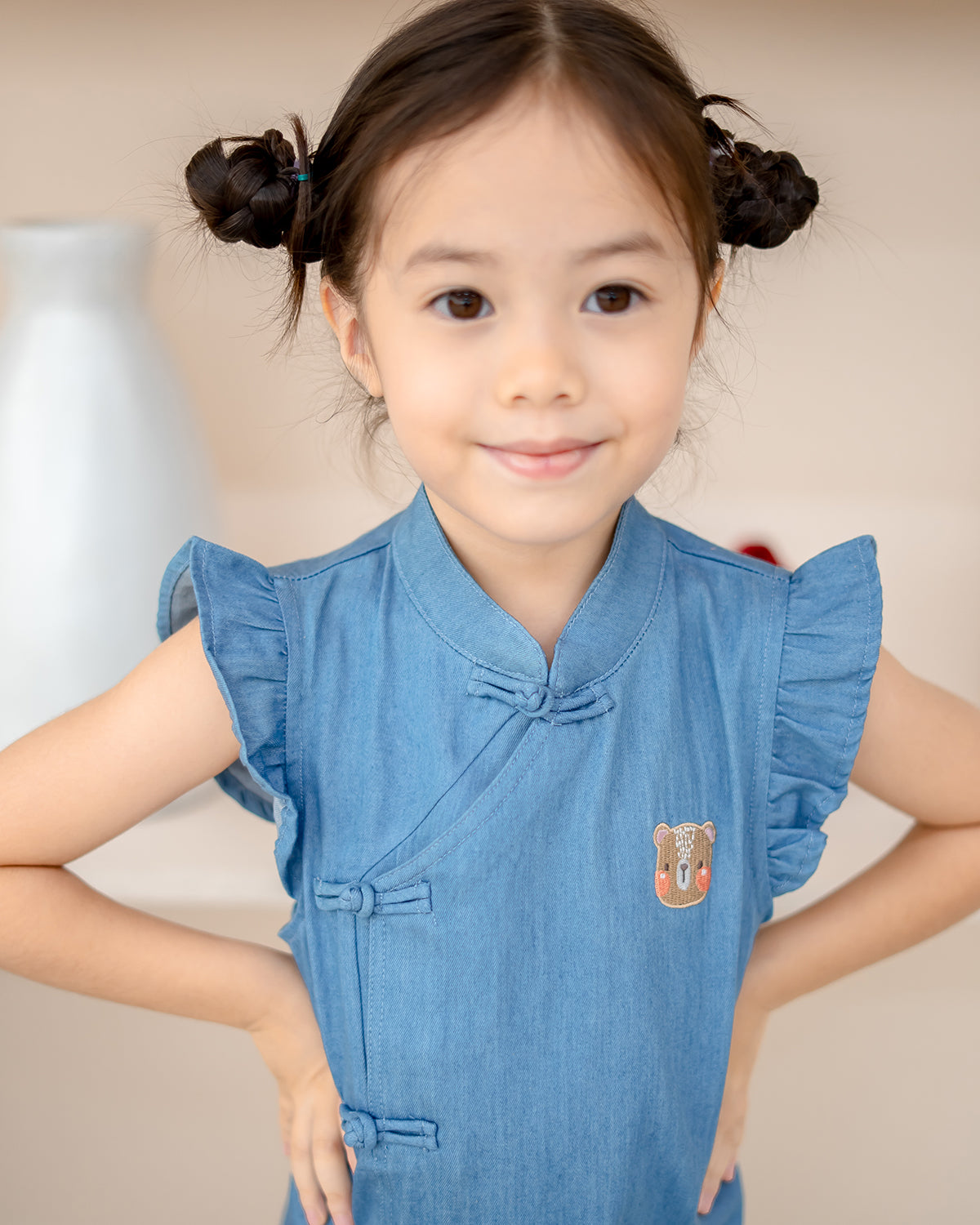 Close-up of kids’ denim cheongsam with knot buttons and LeBear embroidery