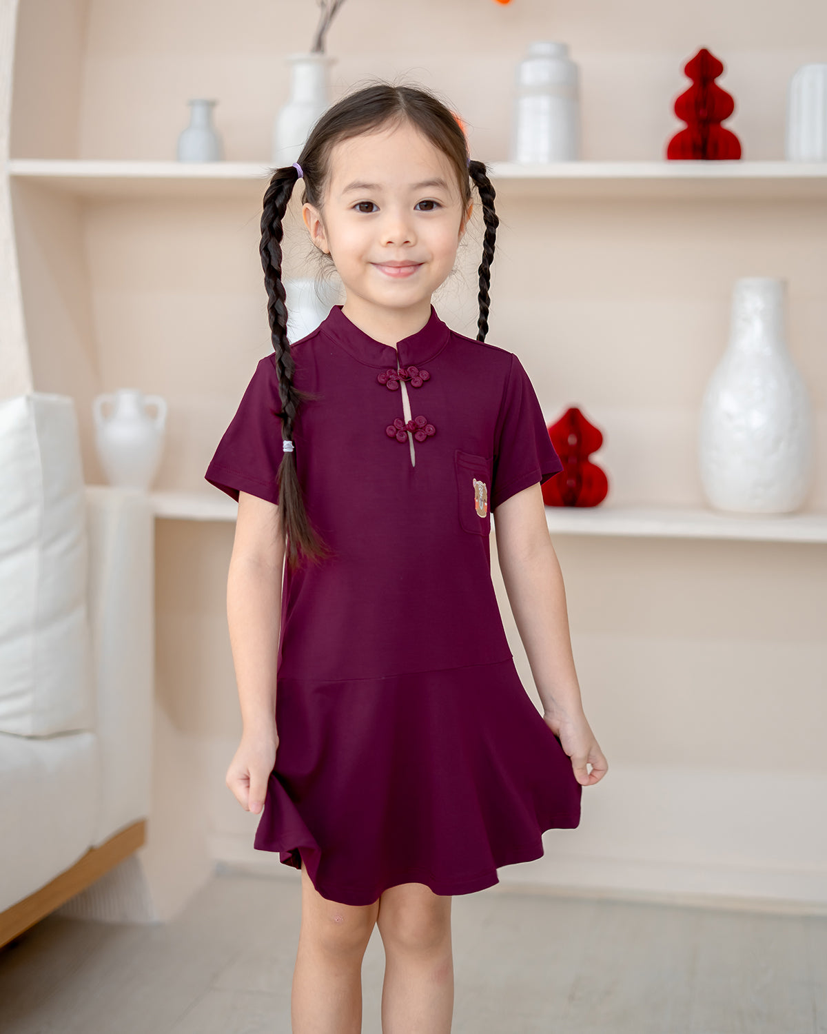Girl smiling in bamboo cheongsam – festive kidswear in plum