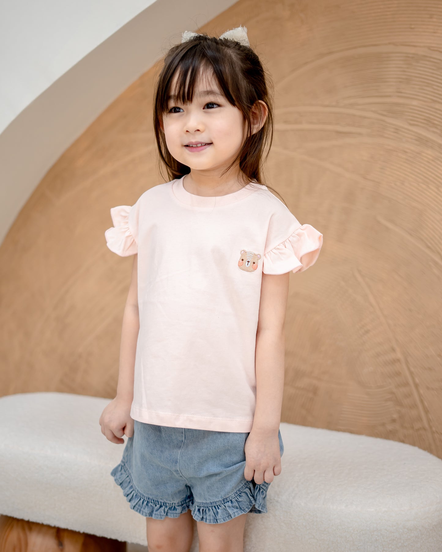 Girl in blush pink Odell cotton top with ruffle sleeves, soft breathable kidswear for everyday comfort