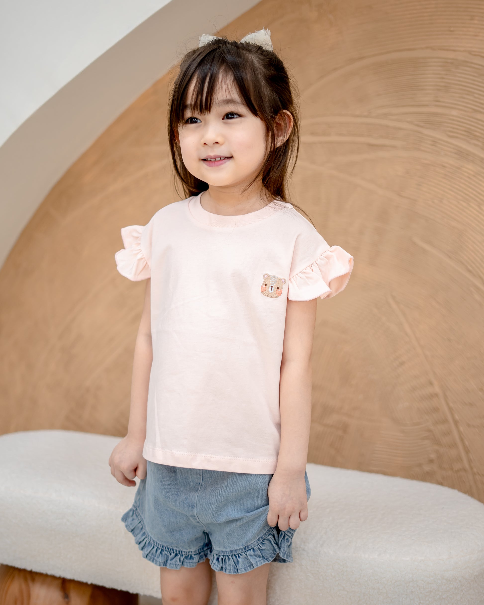 Girl in blush pink Odell cotton top with ruffle sleeves, soft breathable kidswear for everyday comfort