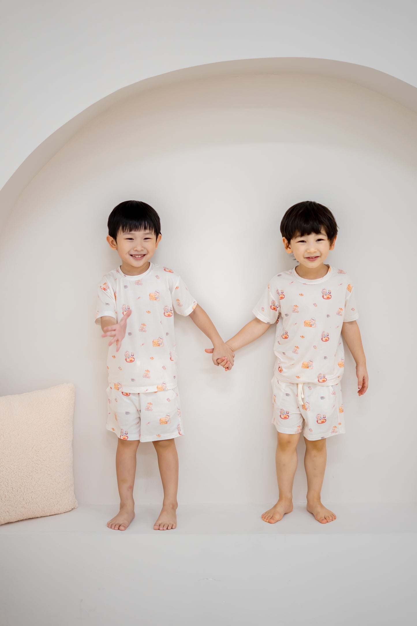 Two children holding hands in matching LeBear Kaya Butter Toast Kids TENCEL™ Lounge Sets with playful print.