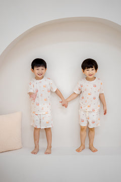 Two children holding hands in matching LeBear Kaya Butter Toast Kids TENCEL™ Lounge Sets with playful print.