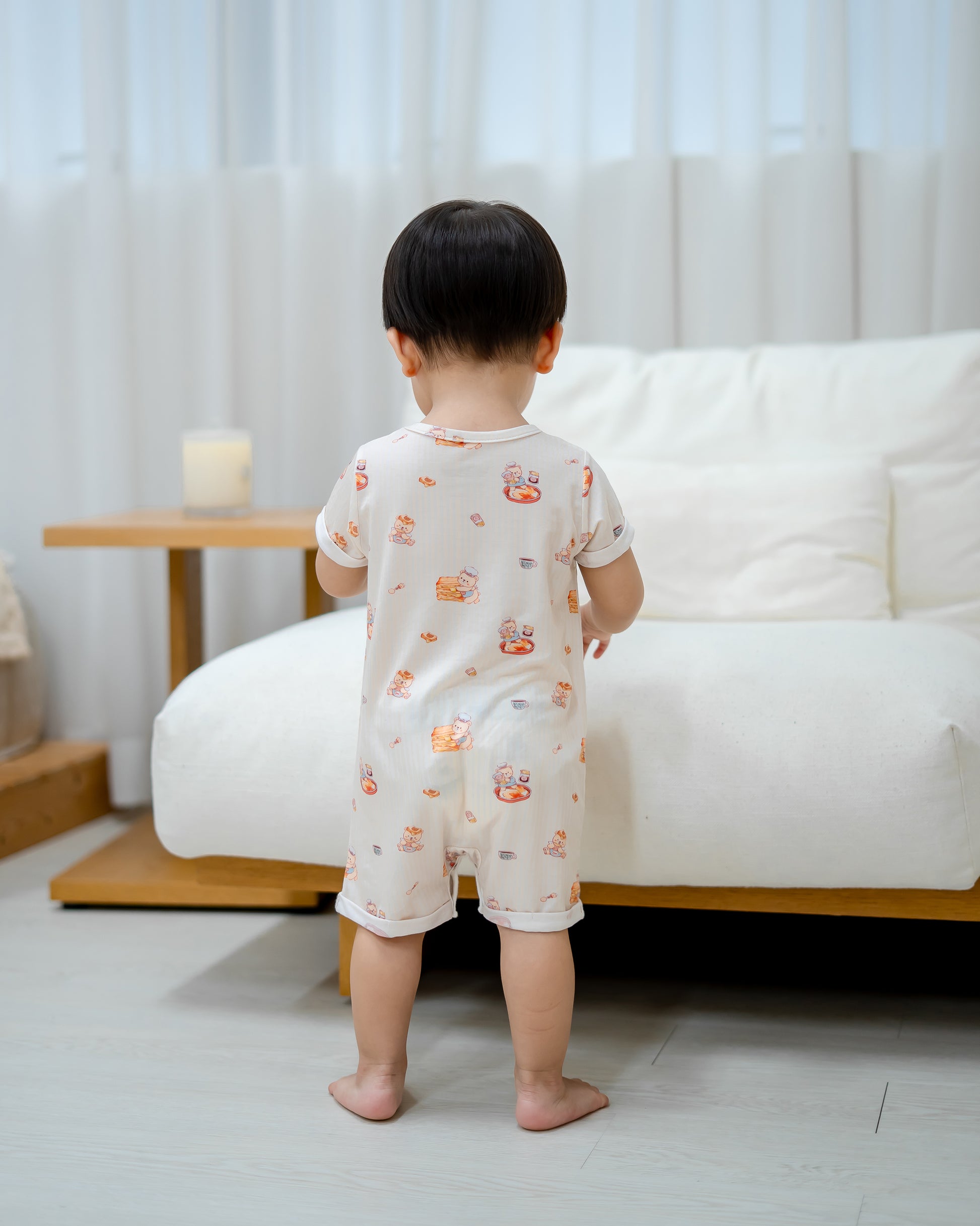 Back view of toddler wearing LeBear Kaya Butter Toast TENCEL™ Baby Onesie showing relaxed fit and full print design.