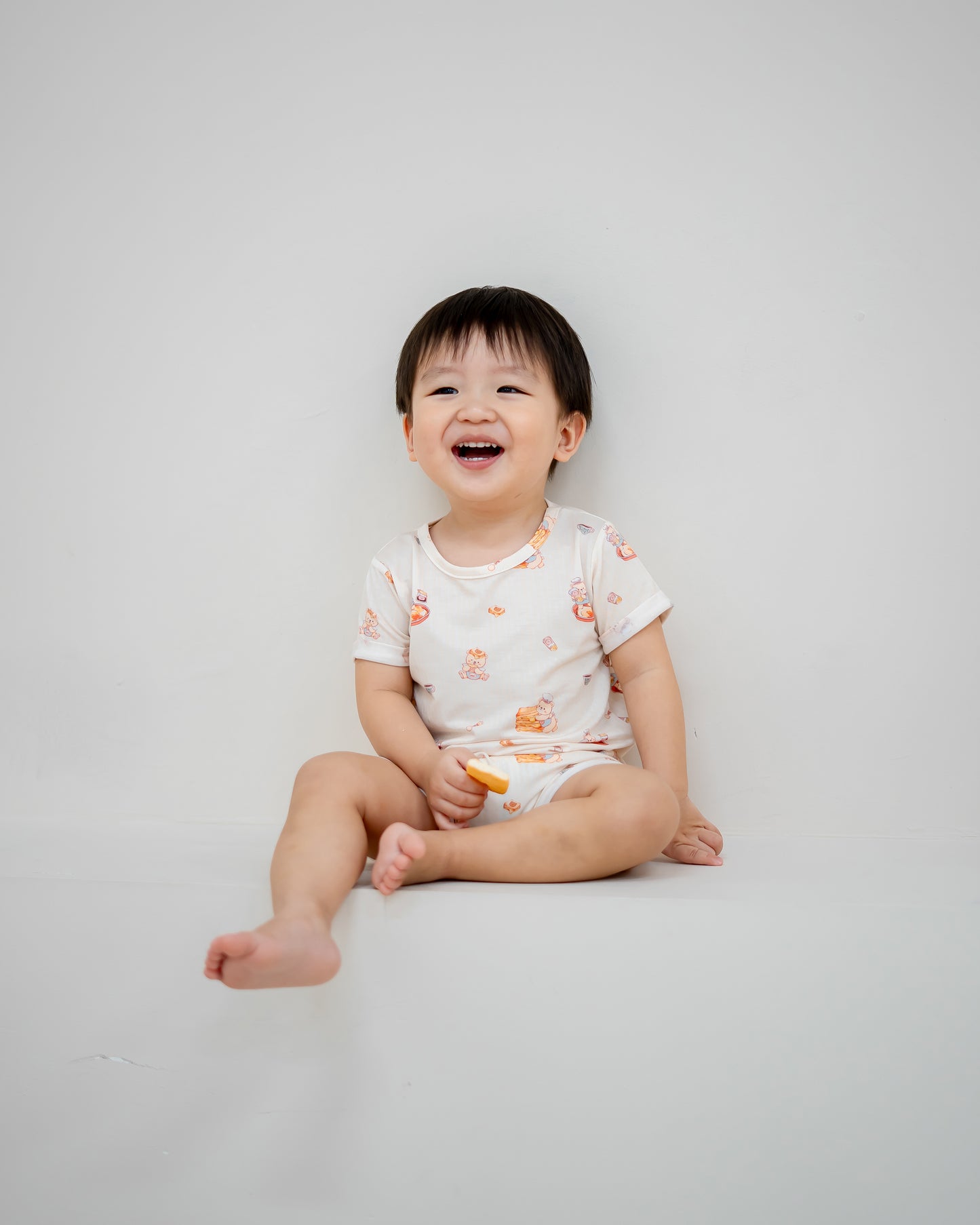 Happy baby laughing while wearing LeBear Kaya Butter Toast TENCEL™ Baby Onesie in soft breathable fabric.