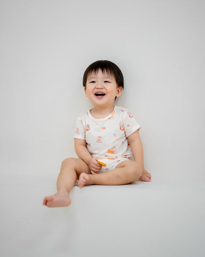 Happy baby laughing while wearing LeBear Kaya Butter Toast TENCEL™ Baby Onesie in soft breathable fabric.