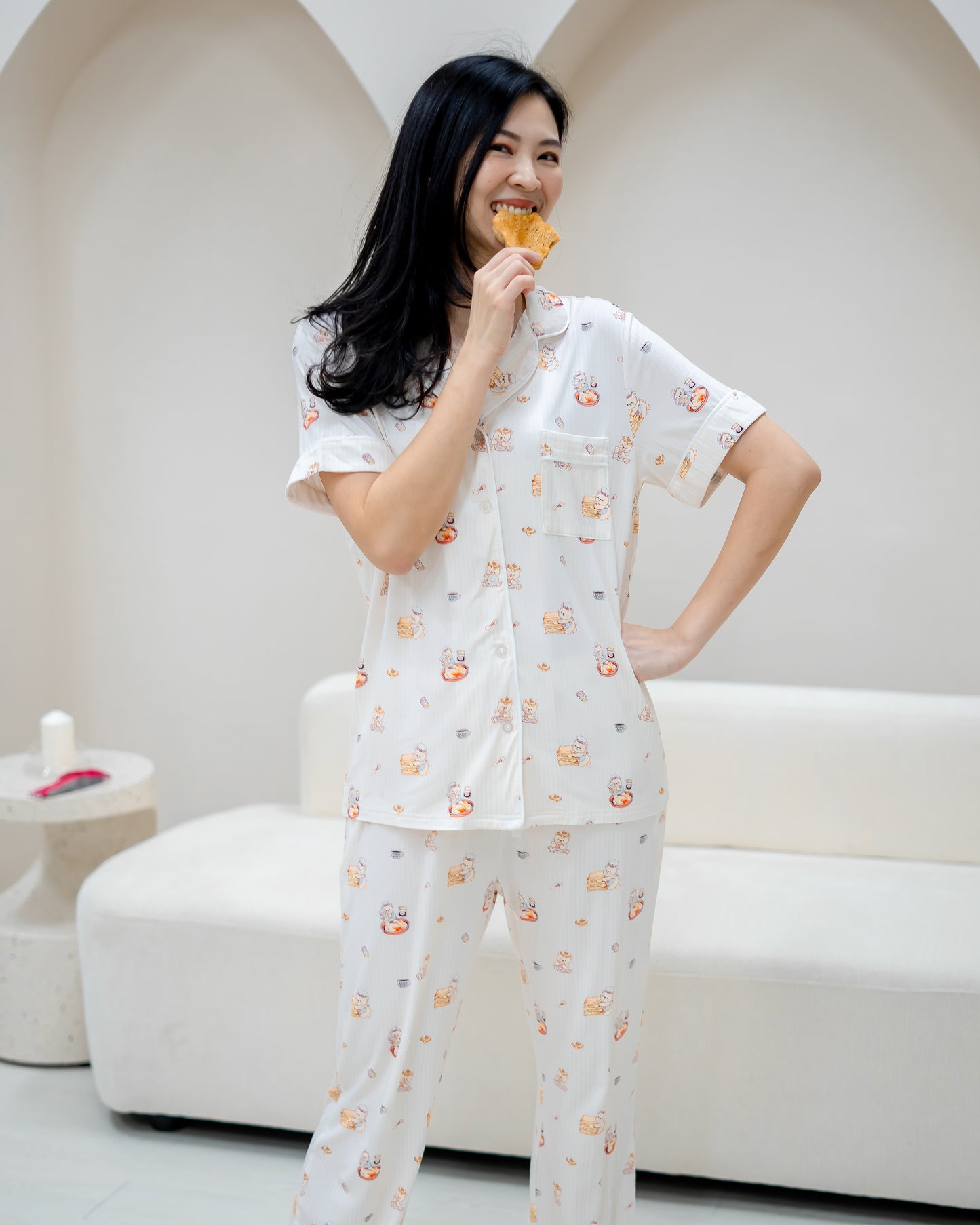 Woman wearing LeBear Adult Kaya Butter Toast Bamboo Pyjamas Pants Set holding toast in playful home setting.