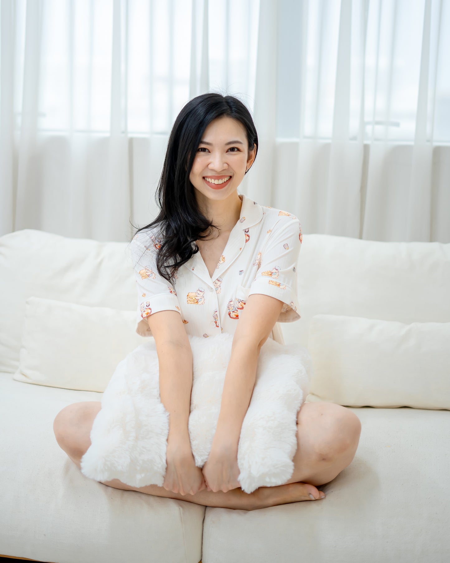Woman sitting on sofa wearing LeBear Adult Kaya Butter Toast Bamboo Pyjamas Shorts Set in soft breathable bamboo fabric.
