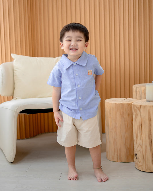 Boy standing in LeBear Atelier Short Sleeve Button Down Shirt Blue