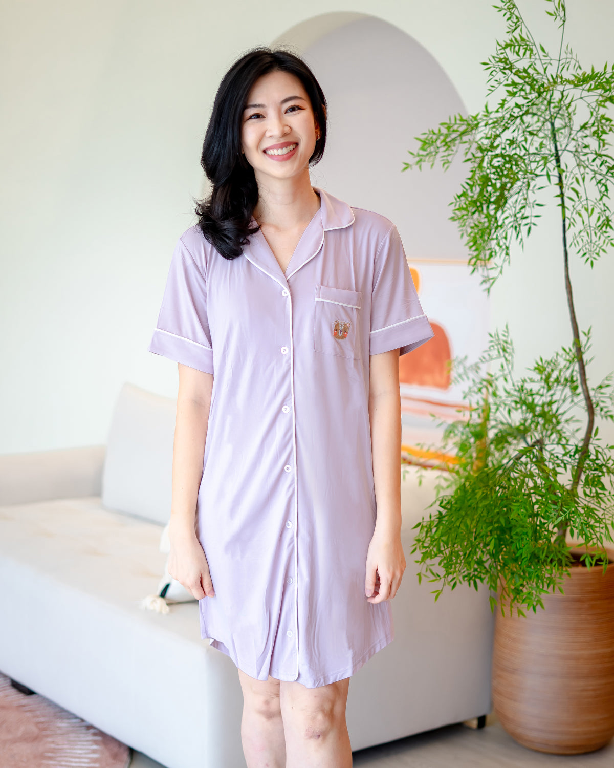 Woman smiling in LeBear lilac bamboo pyjama dress featuring fluffy bear embroidery and relaxed silhouette – eco-friendly sleepwear by LeBear Singapore.