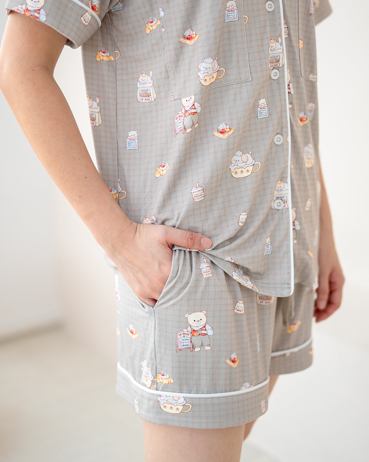 Close-up of LeBear Bearista adult bamboo pyjamas showing the café-inspired teddy bear print on soft beige gingham fabric.
