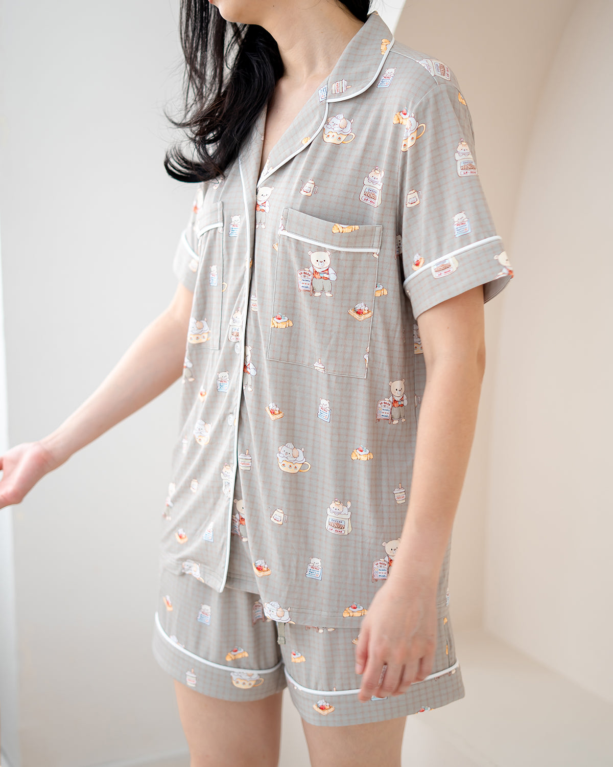 Woman wearing LeBear Bearista adult bamboo pyjamas in beige gingham with exclusive café-themed teddy bear print.