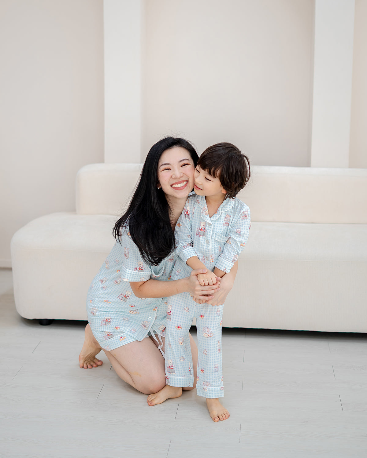 Mother and child wearing matching LeBear Bearista Bluebell Gingham bamboo pyjamas, sharing a joyful family moment.