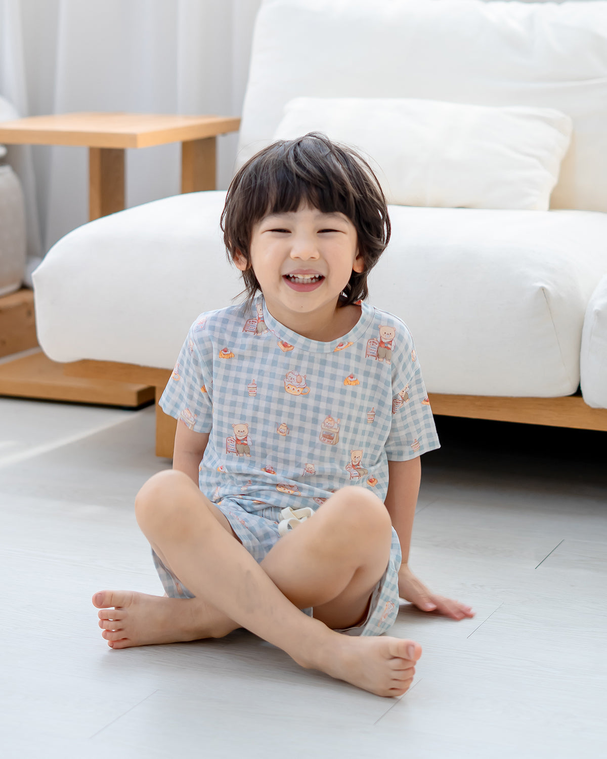 Child wearing LeBear Bearista Bluebell Gingham kids bamboo lounge set in a relaxed seated pose, made from soft and breathable bamboo fabric.