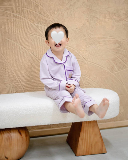 Child wearing LeBear × Em Obsessed OEKO-TEX® bamboo lavender kids pyjamas sitting on a sofa