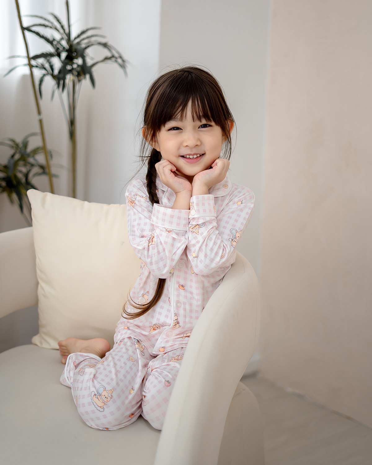 Cute girl posing in LeBear Ice Cream Bear pink gingham bamboo pyjamas in bright modern living room