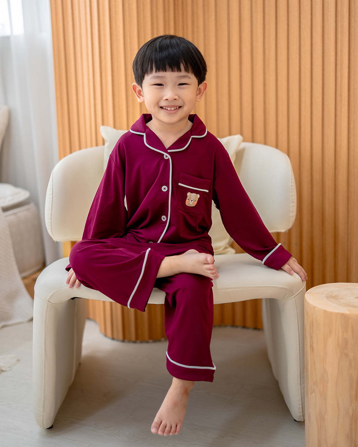 Child sitting in LeBear bamboo wine red pyjamas with contrast piping