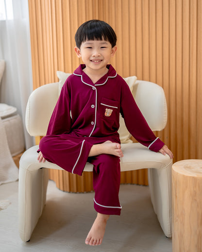 Child sitting in LeBear bamboo wine red pyjamas with contrast piping