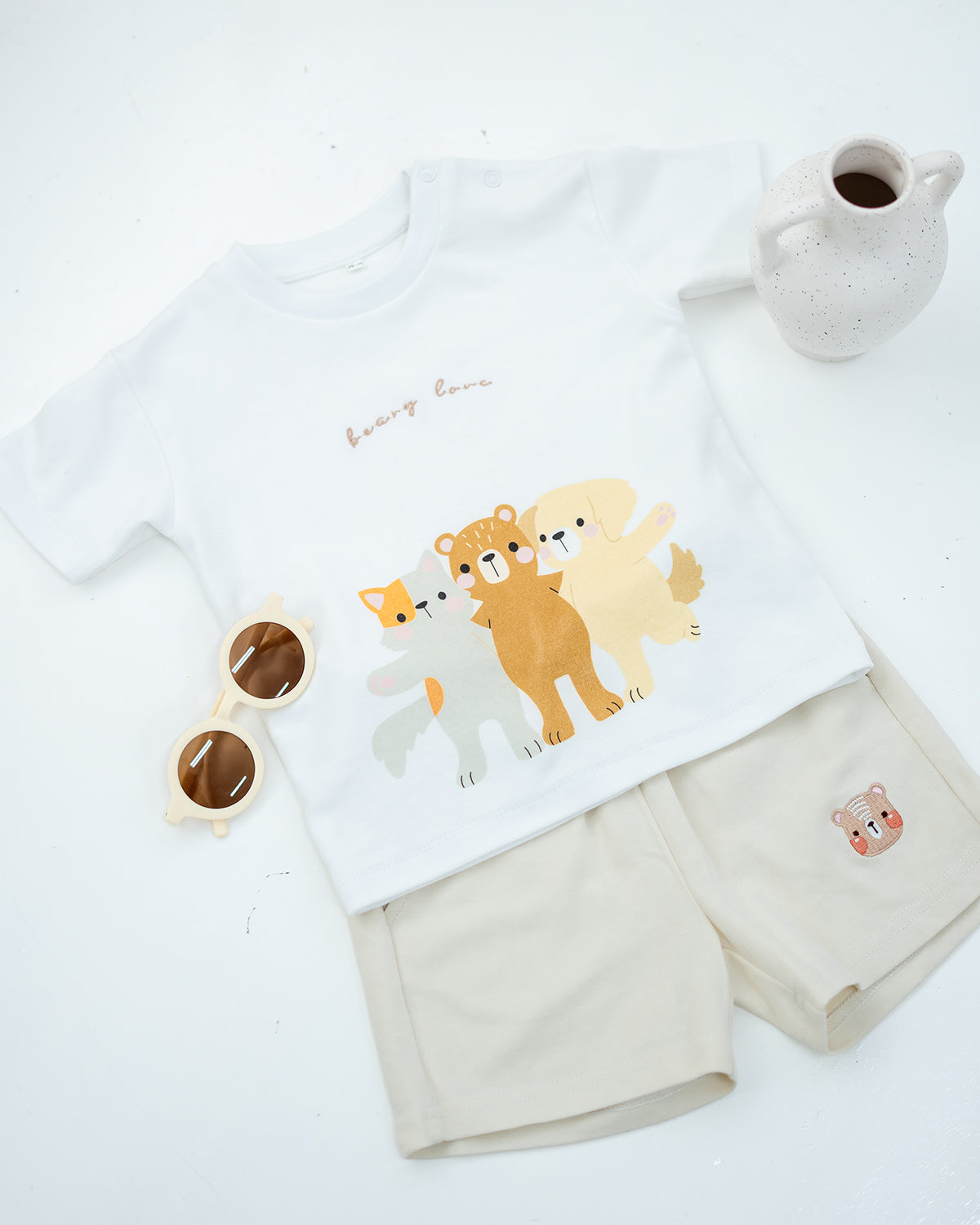 LeBear Kids Bear Friends Tee in white paired with beige bear embroidered shorts, flat lay with accessories