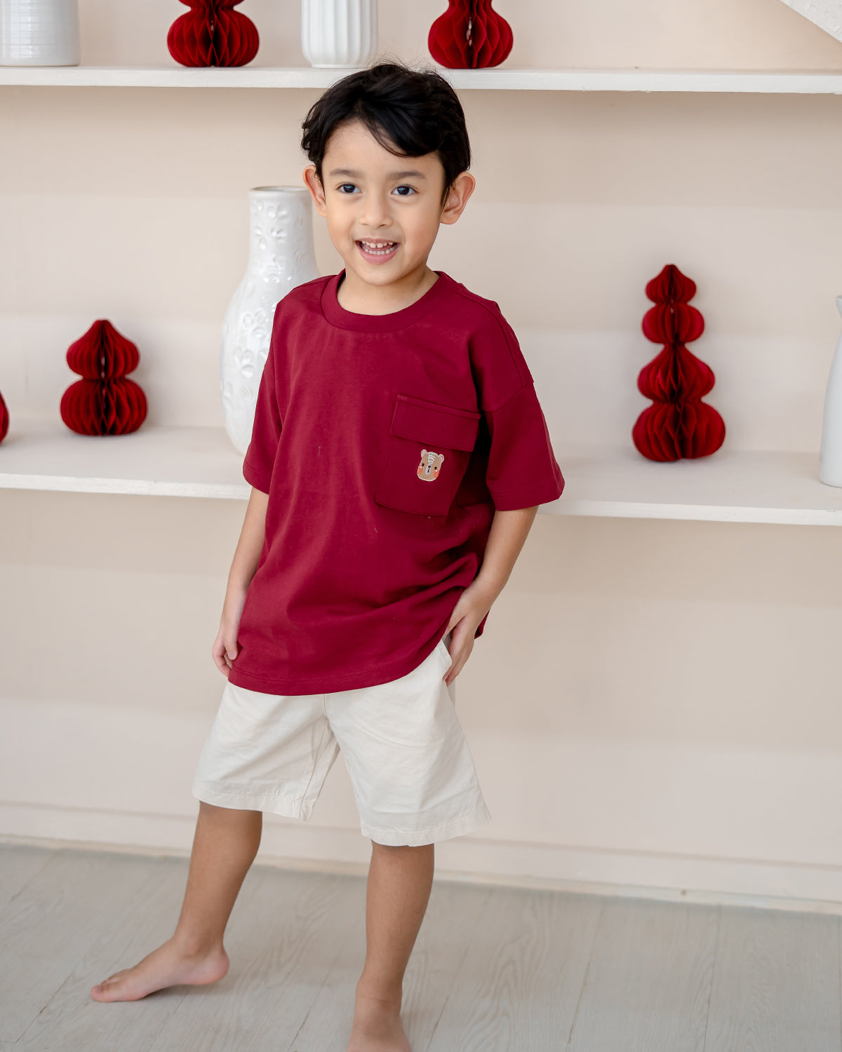 Child posing in LEBEAR red oversized kids tee with pocket embroidery – Lunar Blossom Collection