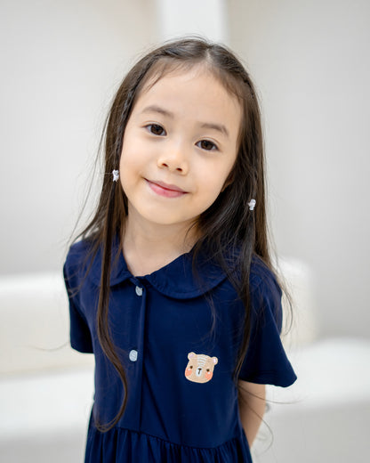Girl wearing LeBear Kids TENCEL™ Collar Dress in Navy with embroidered bear logo and rounded collar front close-up.