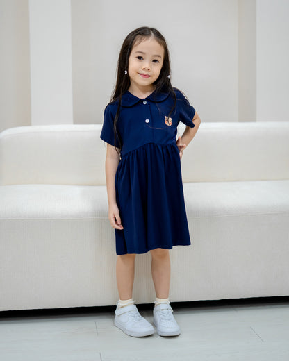 Front pose of girl wearing LeBear Kids TENCEL™ Collar Dress in Navy with signature bear embroidery.
