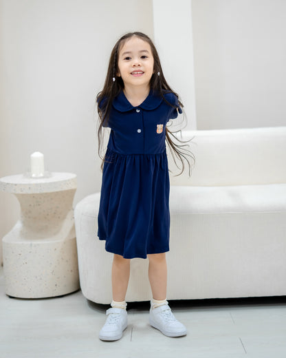 Child smiling in LeBear Kids TENCEL™ Collar Dress in Navy full body view with white sneakers.