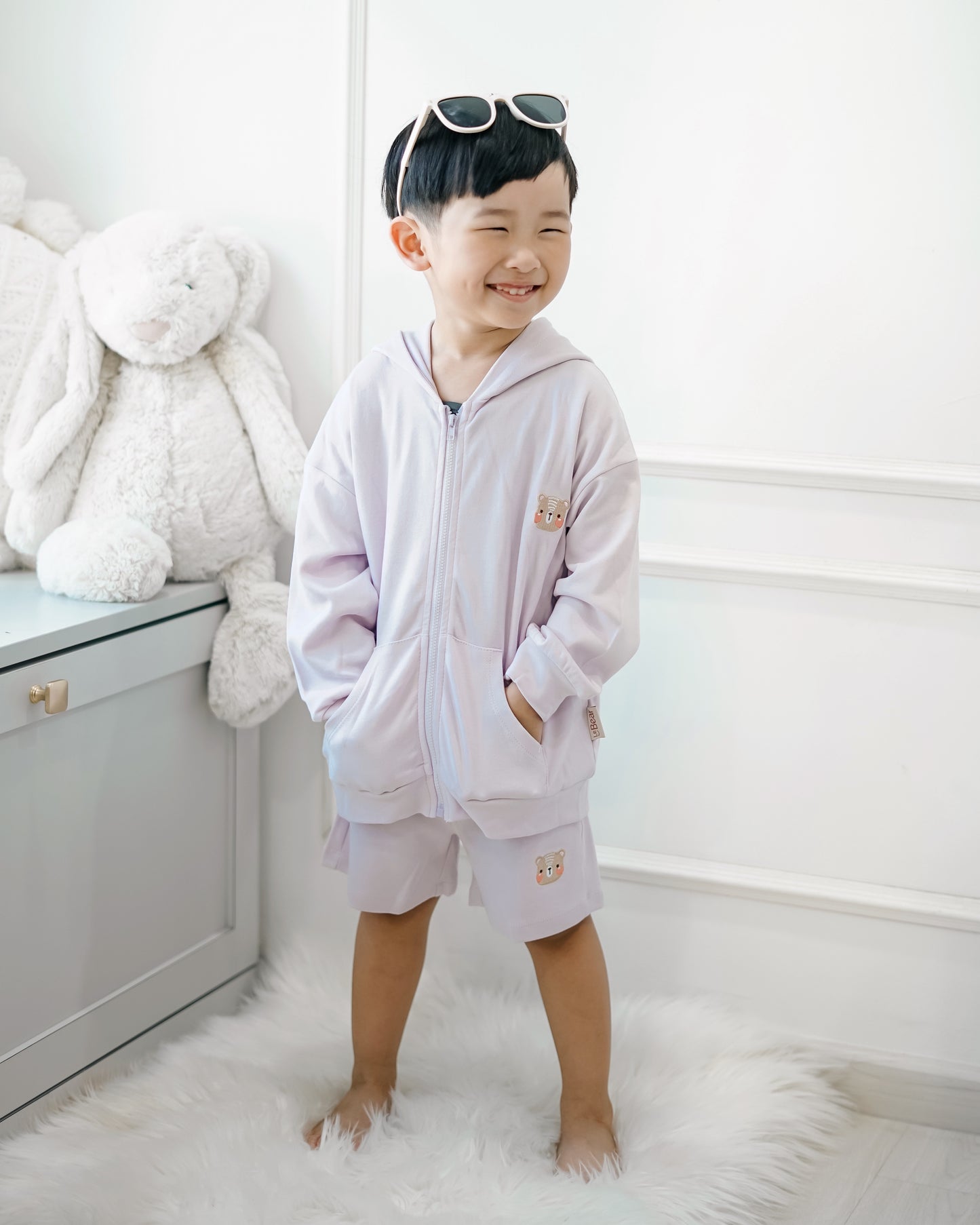 Smiling boy in LeBear lilac premium cotton hooded jacket and shorts set, casual kidswear look