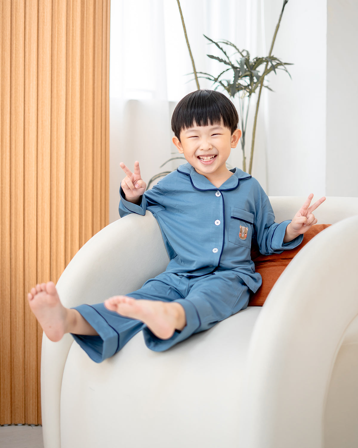 Boy sitting on sofa in LeBear Luxe Bamboo Pyjamas Dusk Blue, tagless eco-friendly kids sleepwear