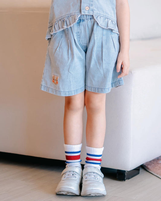 Girl wearing LeBear Mia Ruffle Denim Shorts, soft lightweight cotton denim with tagless design and signature bear detail