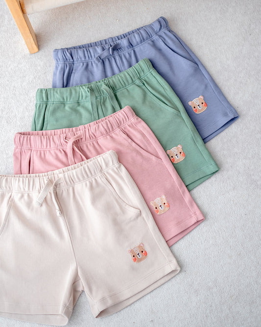 Set of four LeBear premium cotton jogger shorts for kids in lilac blue, sage green, blush pink, and cream beige, soft and breathable fabric.