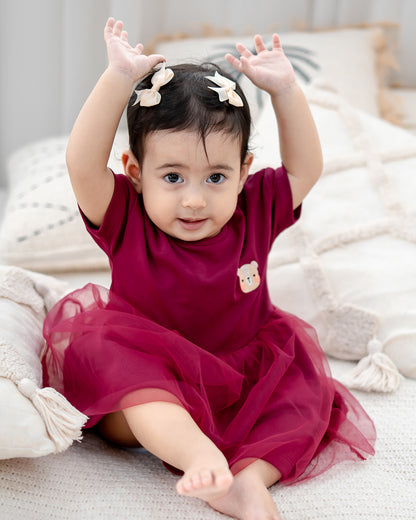toddler wearing lebear roselle tulle dress sitting on bed