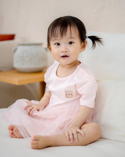 “Toddler sitting in LeBear Roselle Tulle Dress Blush Pink with signature bear embroidery”