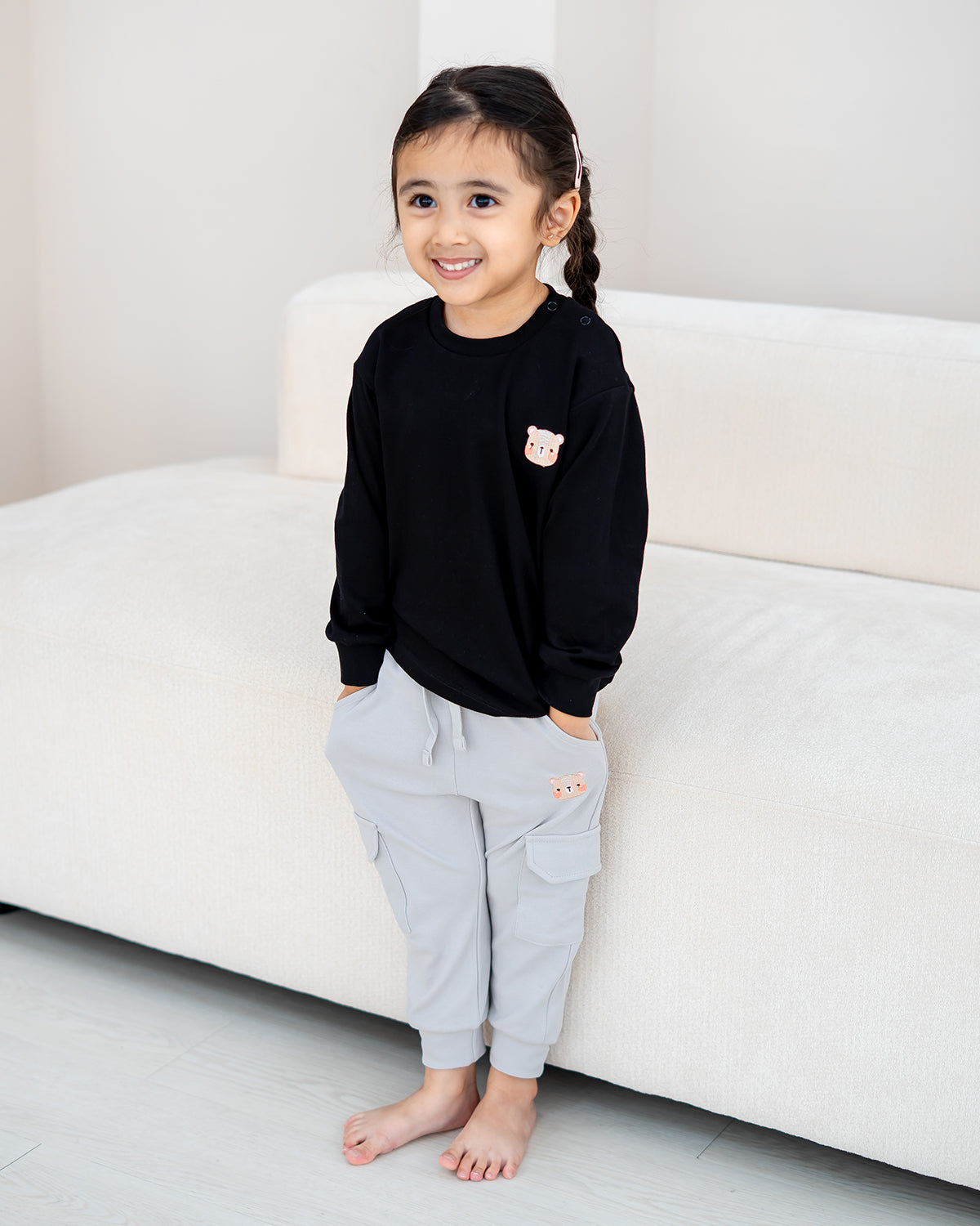 Lifestyle photo of a child wearing the LEBEAR Signature Embroidery Long Sleeve Tee in Black.