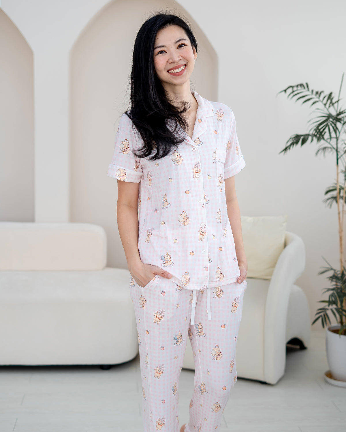Woman wearing LeBear Sweet Scoop adult bamboo pyjamas in soft pink gingham with exclusive teddy bear and ice cream illustrations.