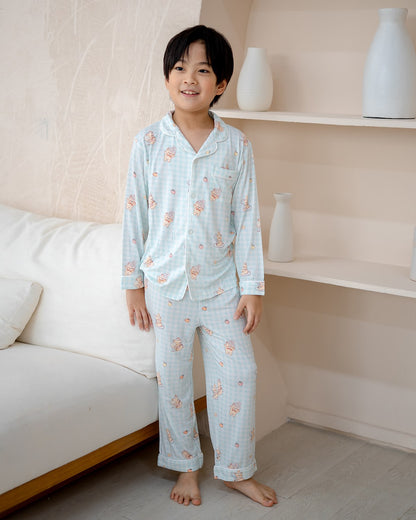 Boy wearing LeBear Sweet Scoops Ice Cream Bear bamboo kids pyjamas with blue gingham print in studio