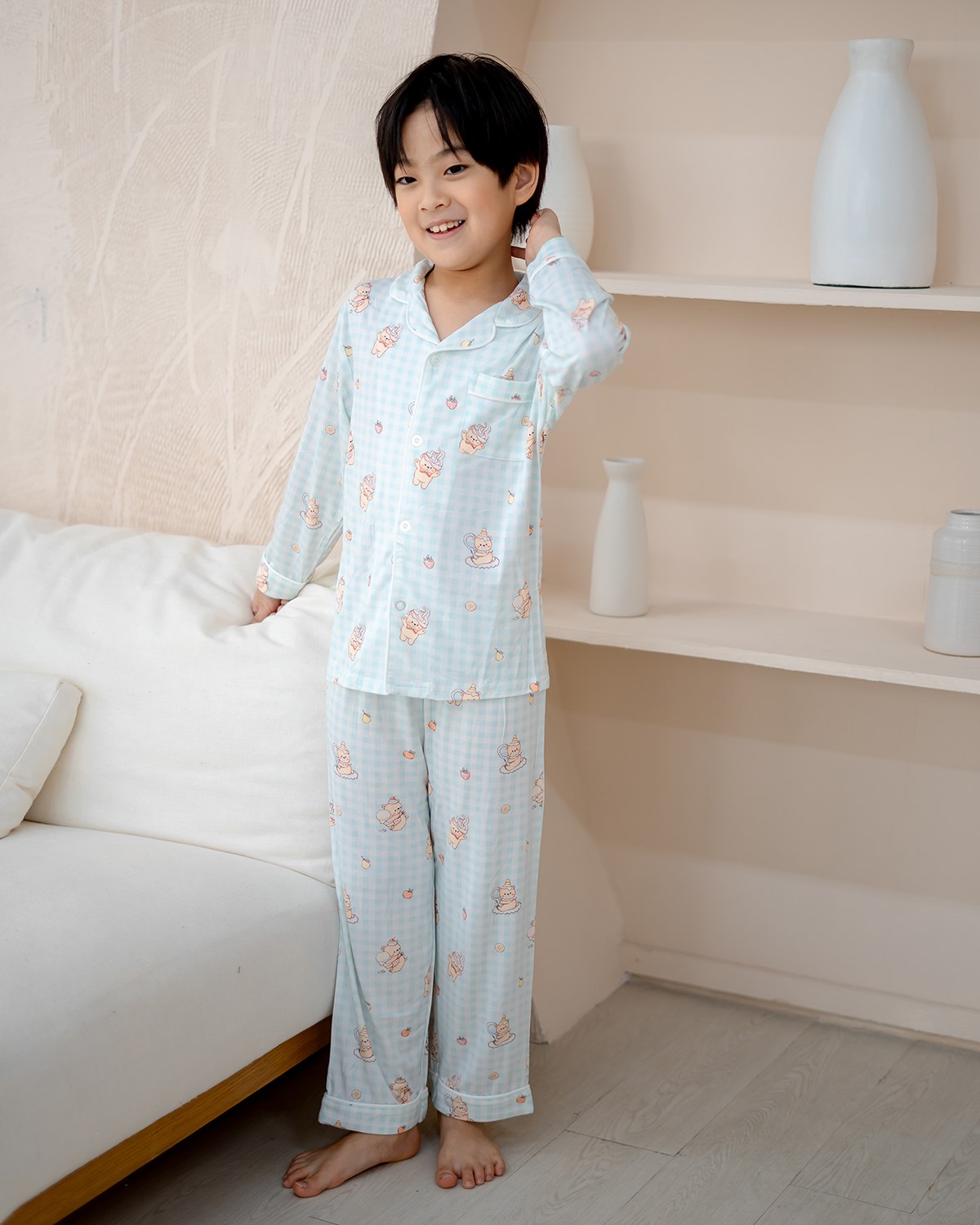 Child model wearing LeBear Sweet Scoops Ice Cream Bear blue gingham bamboo pyjamas standing in modern bedroom