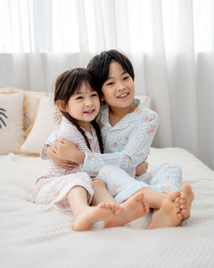 Brother and sister wearing LeBear Sweet Scoops Ice Cream Bear blue and pink gingham bamboo kids pyjamas hugging on bed