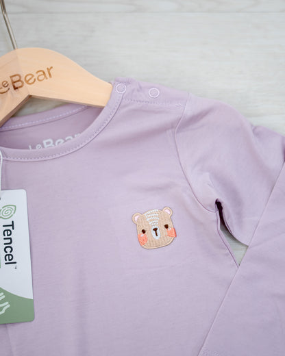 Close-up of LEBEAR signature bear embroidery on TENCEL™ Lilac onesie for babies.