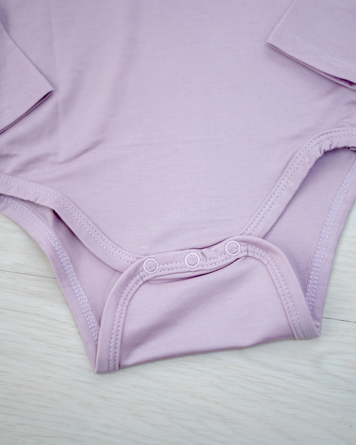Bottom snap closure detail on LEBEAR TENCEL™ Lilac long sleeve bodysuit — gentle and practical baby wear.