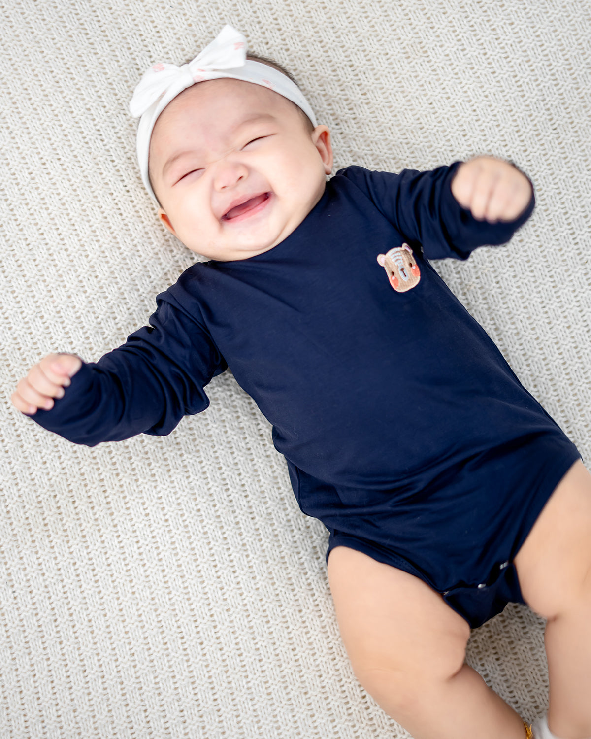 Baby laughing in eco-friendly LEBEAR TENCEL™ Long Sleeve Onesie Navy — gentle on delicate skin.