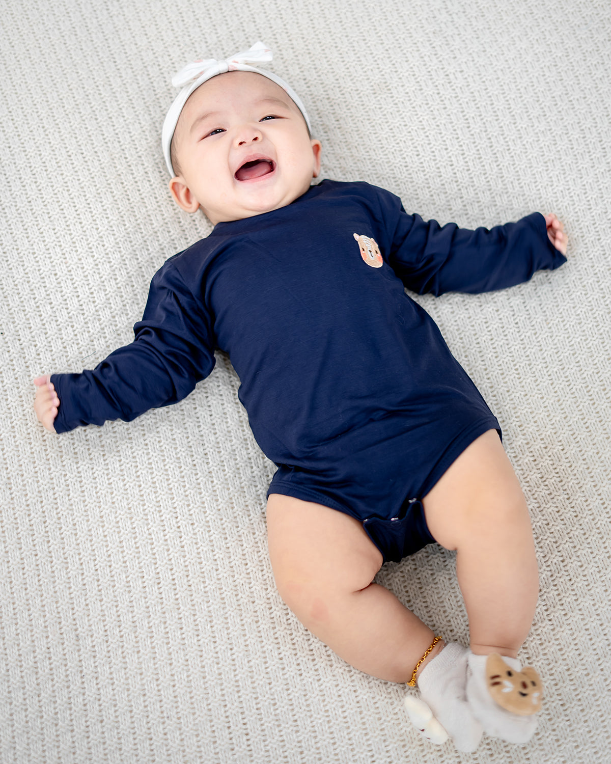 Baby smiling in LEBEAR TENCEL™ Navy long sleeve onesie, ultra-soft and tag-less baby apparel.