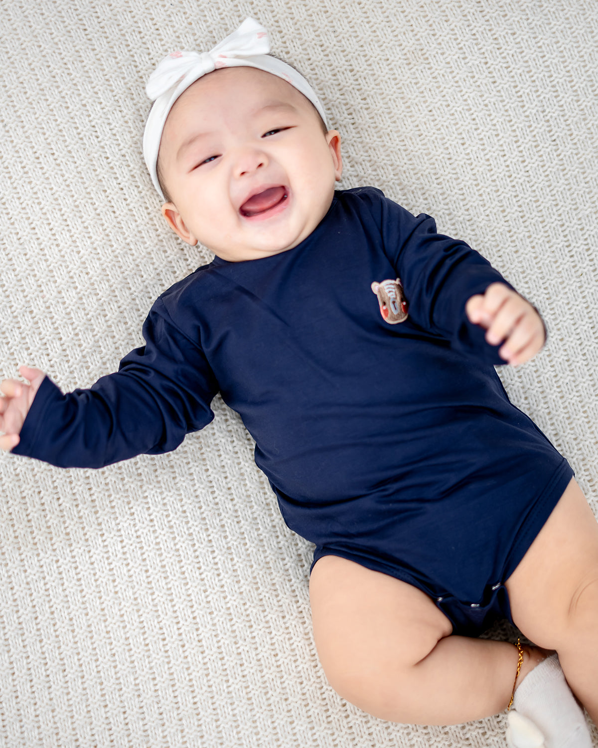 Baby wearing LEBEAR TENCEL™ Long Sleeve Onesie in Navy lying on soft knitted mat — breathable baby romper Singapore.