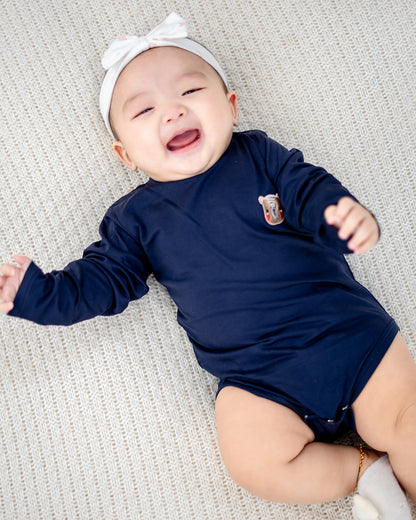 Baby wearing LEBEAR TENCEL™ Long Sleeve Onesie in Navy lying on soft knitted mat — breathable baby romper Singapore.