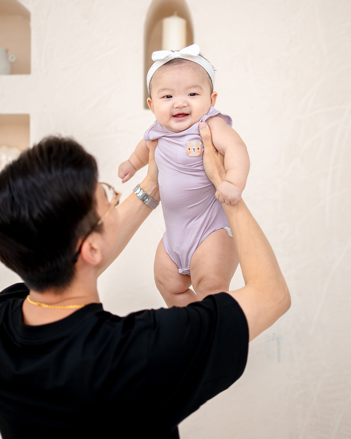 Parent lifting baby in LEBEAR TENCEL™ Lilac onesie — soft, sustainable, breathable baby apparel Singapore.