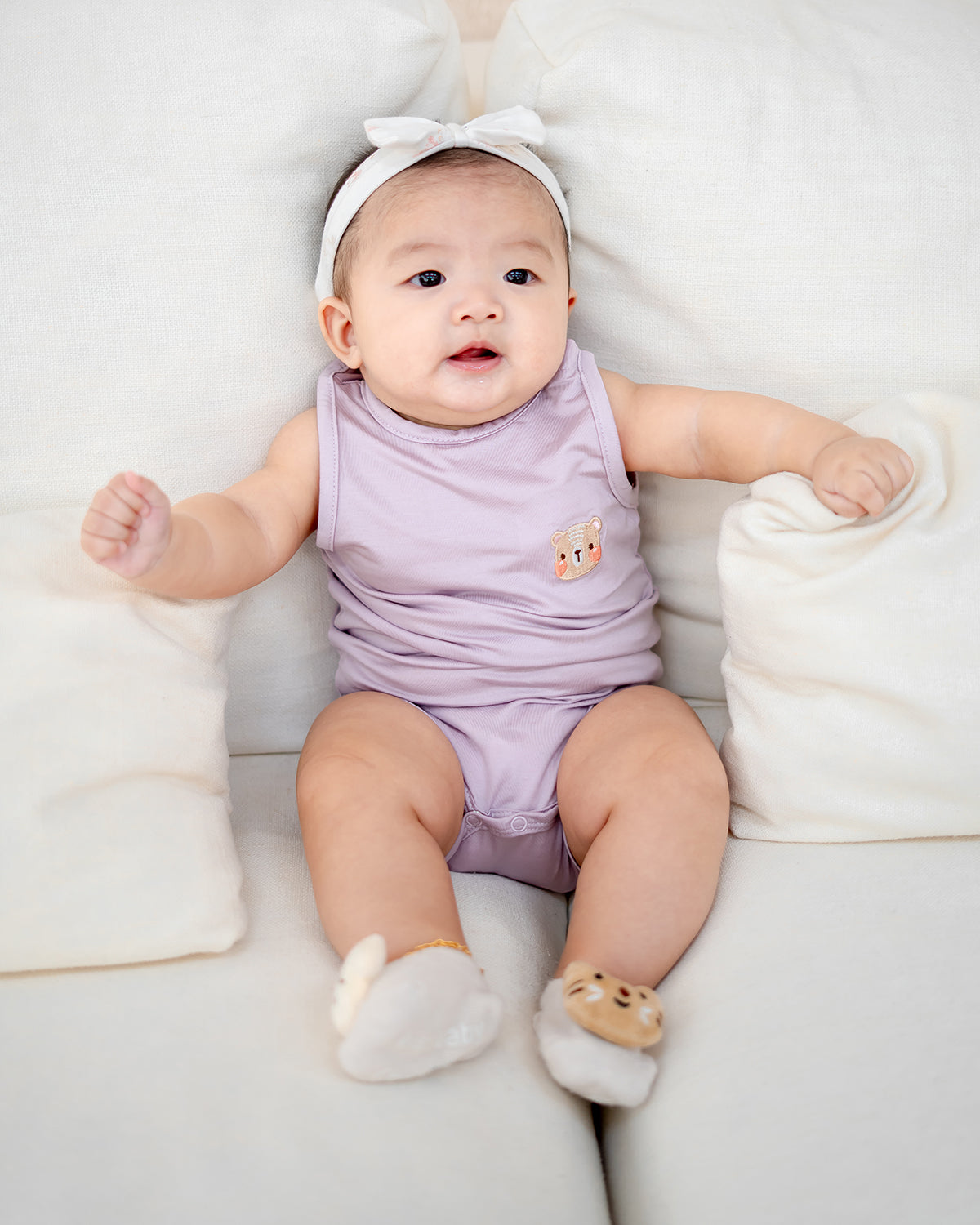 Baby wearing LEBEAR TENCEL™ Tank Onesie in Lilac sitting on sofa — soft breathable baby romper Singapore.