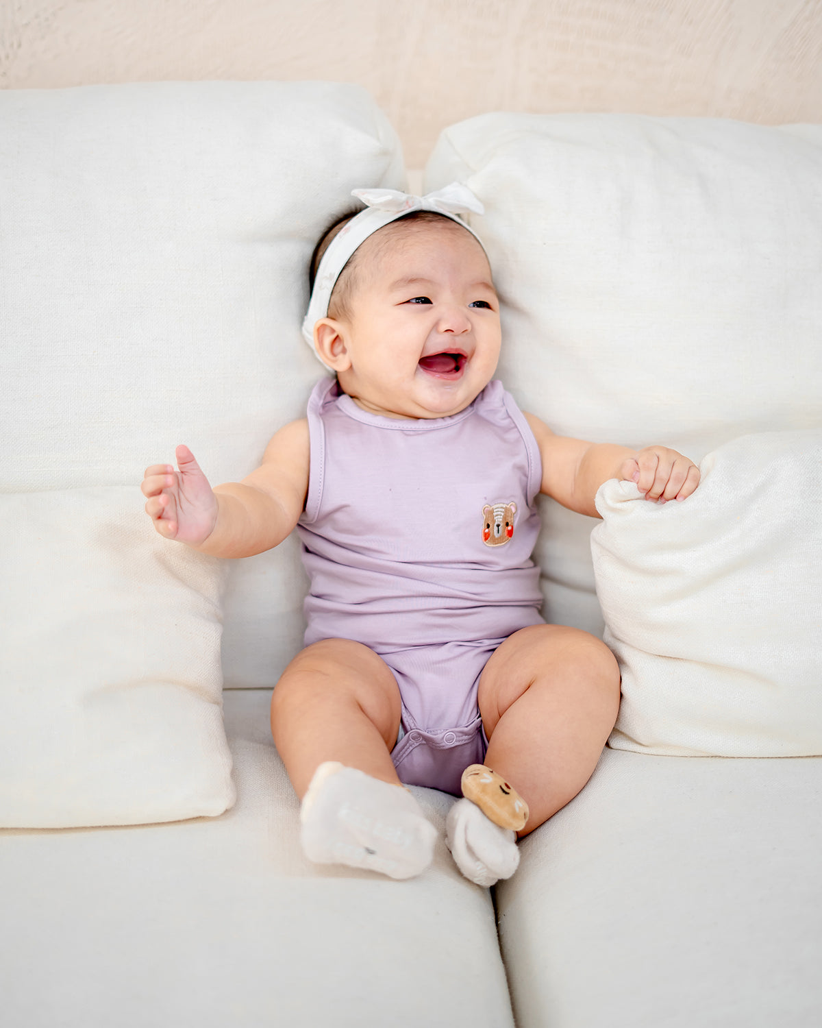 Baby smiling happily in LEBEAR TENCEL™ Lilac onesie, gentle tag-less baby outfit for sensitive skin.