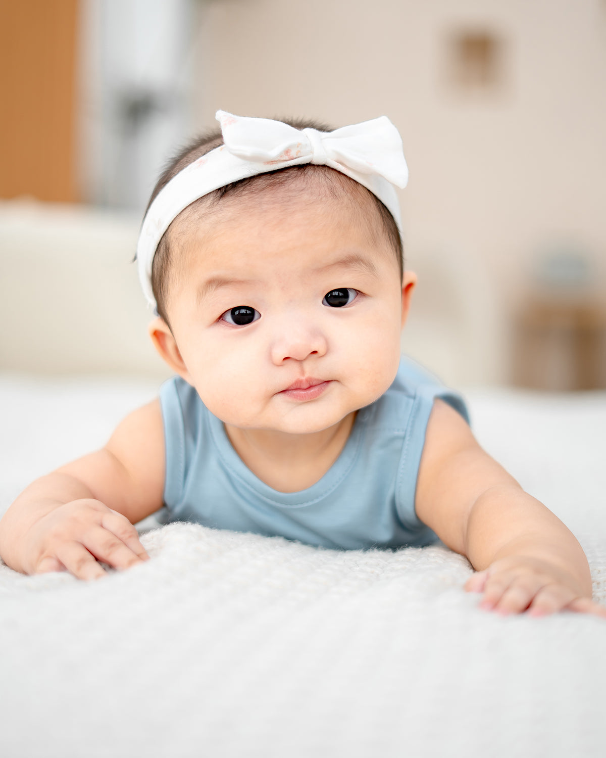 Baby crawling on white blanket in LEBEAR TENCEL™ Sky Blue onesie – soft and eco-friendly baby wear.