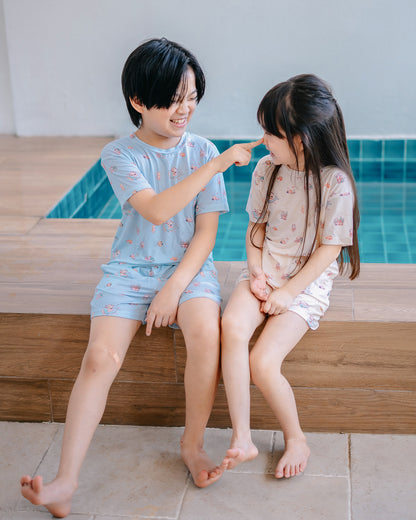 Siblings wearing LeBear Wander & Wonder Kids TENCEL lounge sets beside a pool.